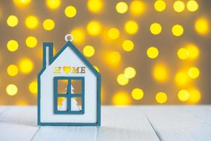 vit leksak trä- hus på gul suddig ljus bokeh bakgrund. jul och ny år begrepp. foto