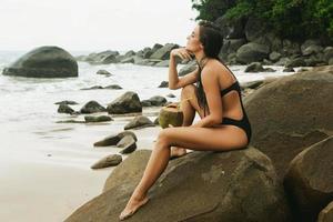 kvinna Sammanträde på de klippig strand foto
