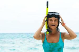 Lycklig kvinna på de strand med mask för snorkling foto