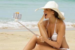 skön kvinna är tar selfie på de strand foto