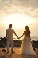 bröllop på de strand - ung gift par innehav händer foto