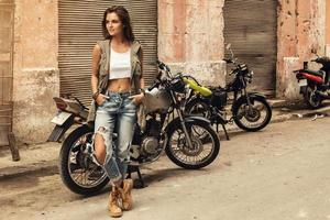 kvinna modell är Framställ bredvid gammal motorcyklar foto