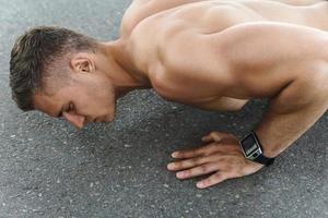 muskulös man är håller på med armhävningar under calisthenic träna på en gata foto