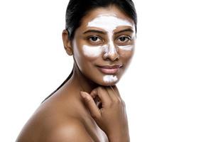 ung indisk kvinna med en rensning mask applicerad på henne ansikte foto