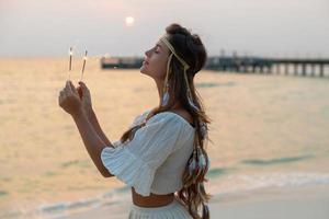 Lycklig kvinna med en sparklers på de strand foto