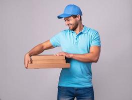 ung leverans man är innehav lådor med en utsökt pizza foto