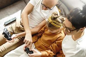 Lycklig familj är spelar video spel trösta på Hem foto