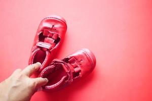kvinnor innehav barns skor på röd bakgrund foto