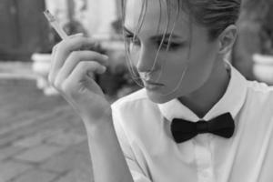 fantastisk kvinna bär rosett slips är rökning cigarett foto