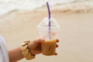 iced kaffe dryck i kvinna hand på strand foto