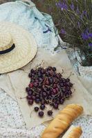 körsbär bär och baguette på de filt under picknick i de lavendel- fält foto
