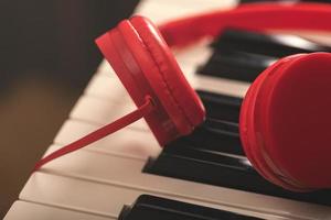 närbild av röd hörlurar över synthesizer tangentbord foto