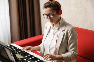 ung kvinna musiker spelar synthesizer på Hem foto