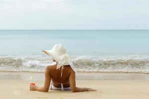 kvinna bär bredbrättad hatt är Sammanträde på de strand foto