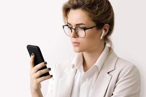 ung affärskvinna talande förbi telefon använder sig av trådlös öronsnäckor foto