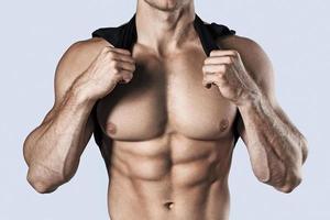 kroppsbyggare som visar hans muskulös torso mot grå bakgrund foto