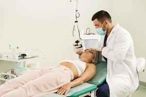läkare hudläkare och kvinna klient under laser hud återytas behandling foto