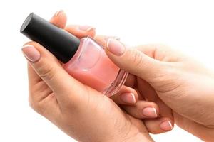 kvinna händer med skön franska manikyr innehav flaska av rosa nagel putsa mot vit bakgrund foto