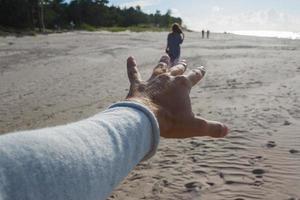 punkt av se skott av man nå hand för kvinna på hav Strand. foto