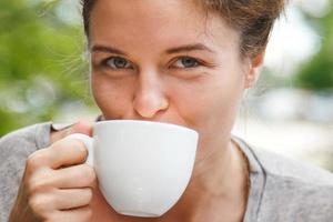 ung Söt kvinna dricka coffe i öppen luft Kafé. foto