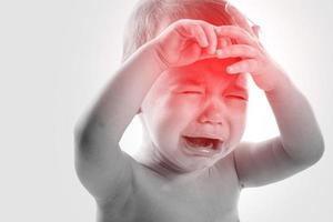 liten gråt bebis lidande från en huvudvärk foto