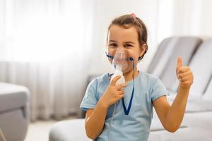 liten flicka framställning inandning med nebulisator på Hem. barn astma inhalator inandning nebulisator ånga sjuk hosta begrepp horisontell foto