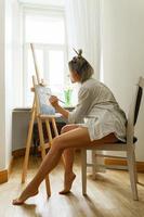 ung kvinna konstnär målning på duk på de staffli foto