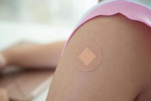 vaccinerade liten asiatisk flicka med lim plåster efter vaccin injektion foto