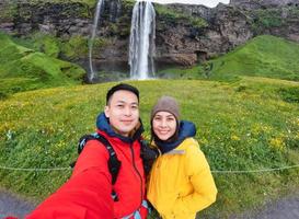 ung asiatisk par turist selfie med kamera i vattenfall känd plats på sommar foto