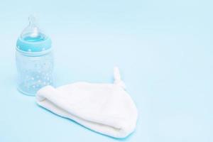flaska med en napp och en keps för en bebis på en blå bakgrund med kopia Plats foto