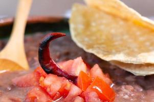 bönor kokta i en lera maträtt med tomat och tortillas, mexikansk fattig maträtt foto