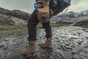 lady med ryggsäck gående tvärs över grund bäck naturskön fotografi foto