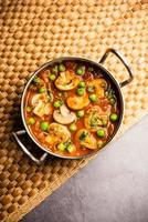 svamp och ärta curry med rostad vitlök, indisk mat eras i en skål foto