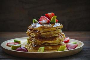 pannkaka jordgubb avokado frukt och honung sirap ljuv efterrätt på trä tabell panorera kaka efterrätt hemlagad foto