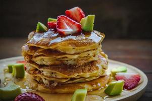 pannkaka jordgubb avokado frukt och honung sirap ljuv efterrätt på trä tabell panorera kaka efterrätt hemlagad foto