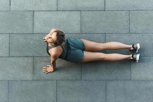 atletisk kvinna är håller på med yoga övningar under träna på en gata foto