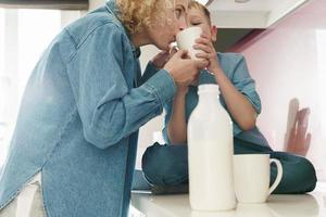 mor och henne söt son dricka mjölk på de kök foto