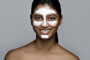 ung indisk kvinna med en rensning mask applicerad på henne ansikte foto