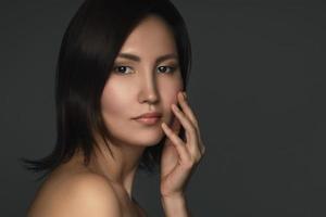 porträtt av ung och skön asiatisk kvinna på grå bakgrund foto