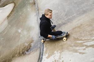 ung handikappade kille med en longboard i en skatepark foto