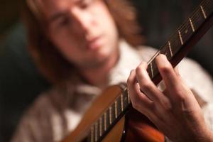 ung musiker spelar hans akustisk gitarr foto