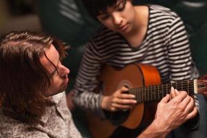 ung musiker lär kvinna studerande till spela de gitarr foto