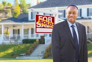 afrikansk amerikan ombud i främre av skön beställnings- hus och såld för försäljning verklig egendom tecken. foto