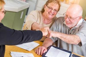 senior vuxen par fira med näve stöta över dokument i deras Hem med ombud på signering foto