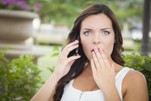 chockade ung vuxen kvinna talande på cell telefon utomhus foto