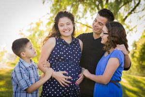 Lycklig attraktiv latinamerikan familj med deras gravid mor utomhus foto