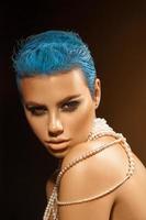 trevlig ung vuxen kvinna med kort blå frisyr och pärlor på nacke foto