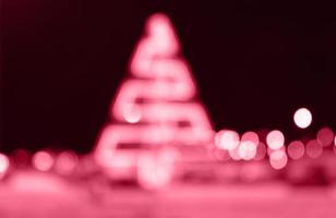 suddig festlig bakgrund tillverkad med jul illumination. färgrik magenta jul träd och bokeh av de ofokuserad, bokeh på natt bakgrund. Färg av de år 2023 - viva magenta foto