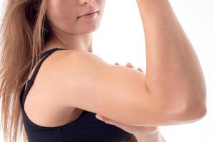 ung flicka visar av henne biceps på ärm närbild foto