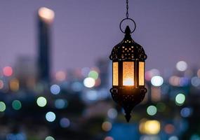 hängande lykta med natt himmel och stad bokeh ljus bakgrund för de muslim fest av de helig månad av ramadan kareem. foto